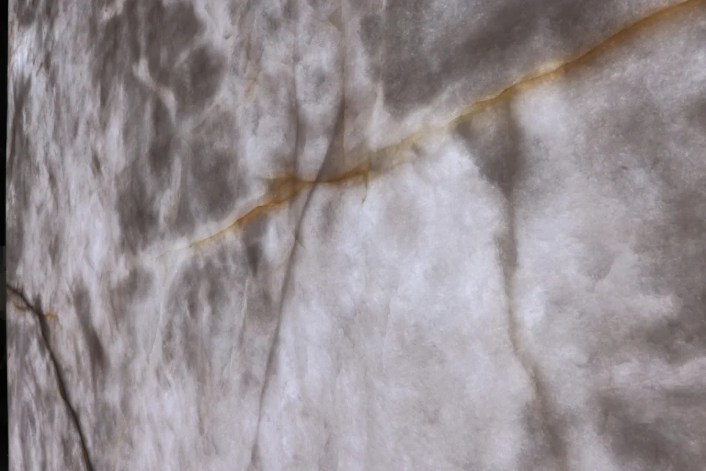 Close view of a white, cloudy, semi-translucent stone crossed by a thin amber vein