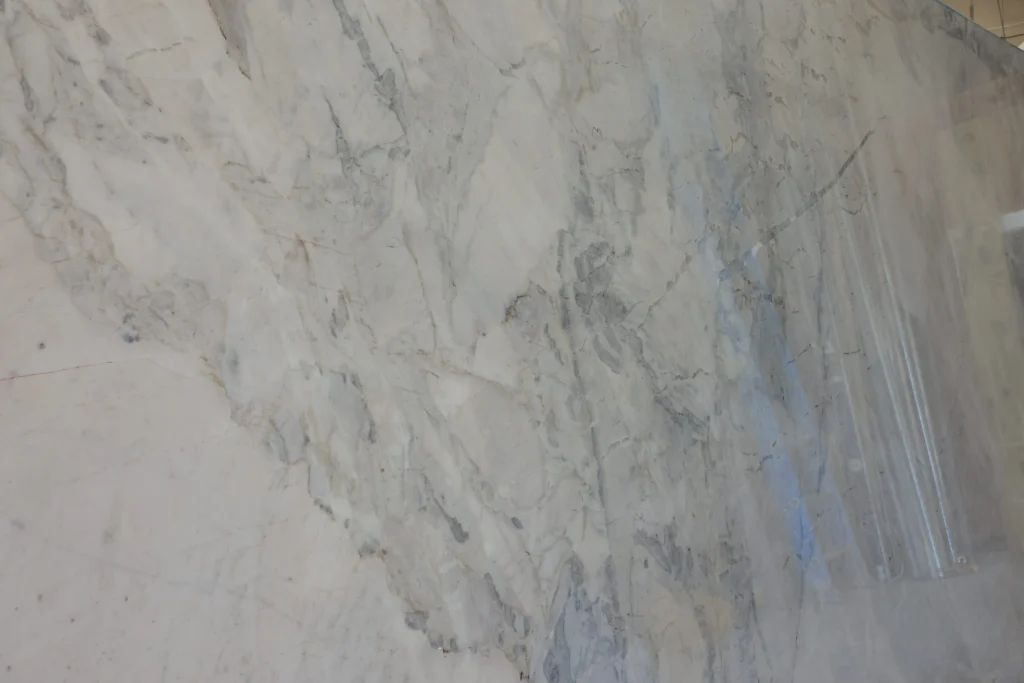 Polished white slab with soft gray and blue-gray veining standing upright in the warehouse